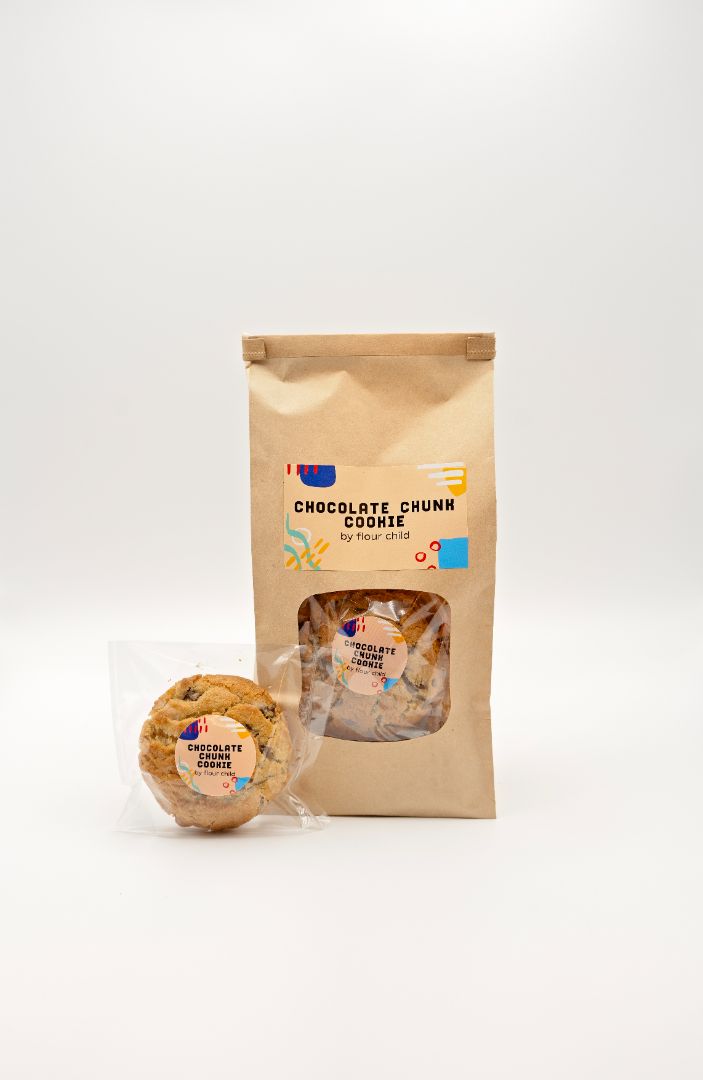 A package of Chocolate Chunk Cookies with one cookie visible in front of the package, both placed on a white background.