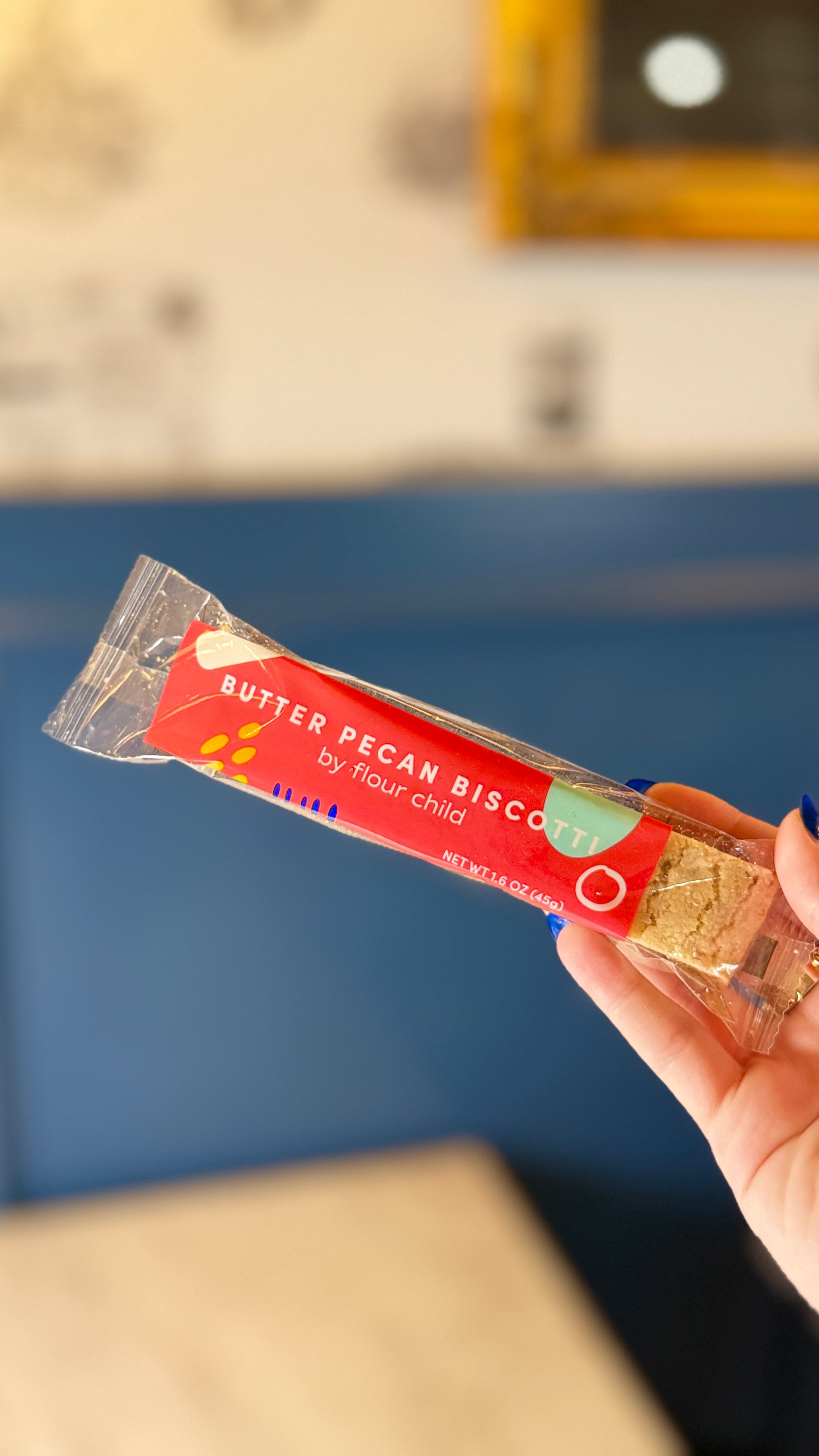 an individually wrapped butter pecan biscotti being held up in the air
